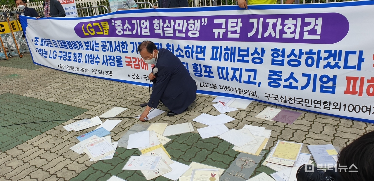 김성수 LG피해자협의회 회장이 LG그룹의 갑질에 대한 항의 표시로 바닥에 뿌린 특허권을 들여다보고 있다.